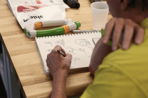 Industrial design student sitting at a desk sketching on drawing pad.