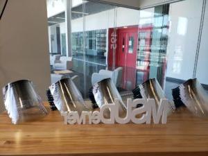 3D printed face shields and MSU Denver logo sitting on a table