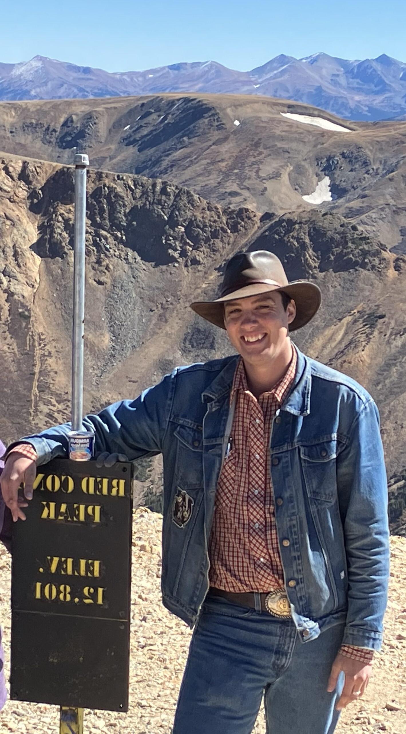 Ben Brown smiling on top of a mountain.